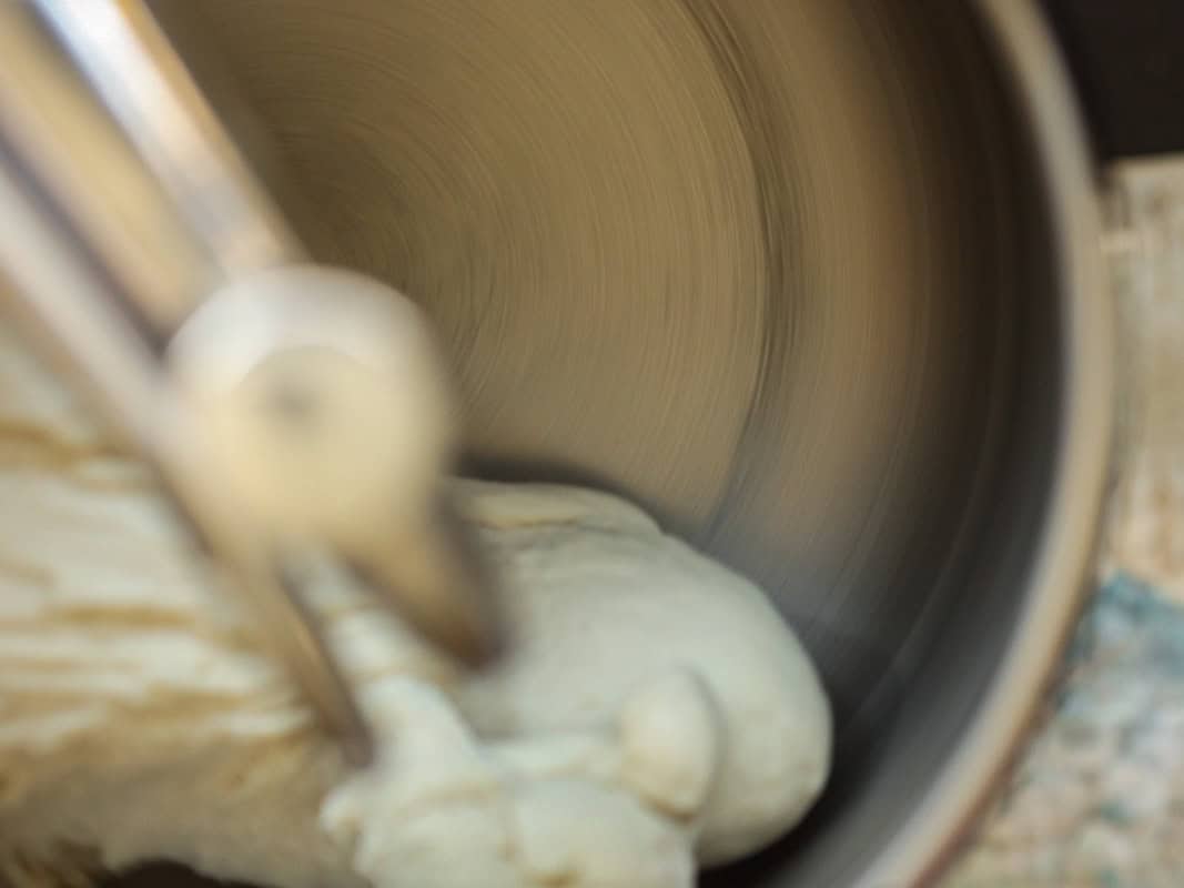 A close-up of a standmixer in motion, with a partially formed dough